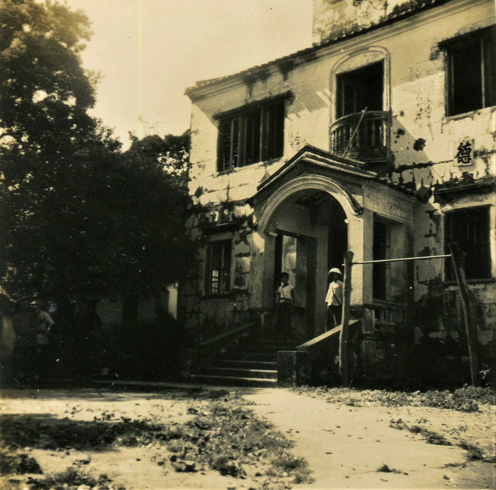 2 story building, dirt road, trees. The East River Column Headquarters in Shenzhen, ca 1943.