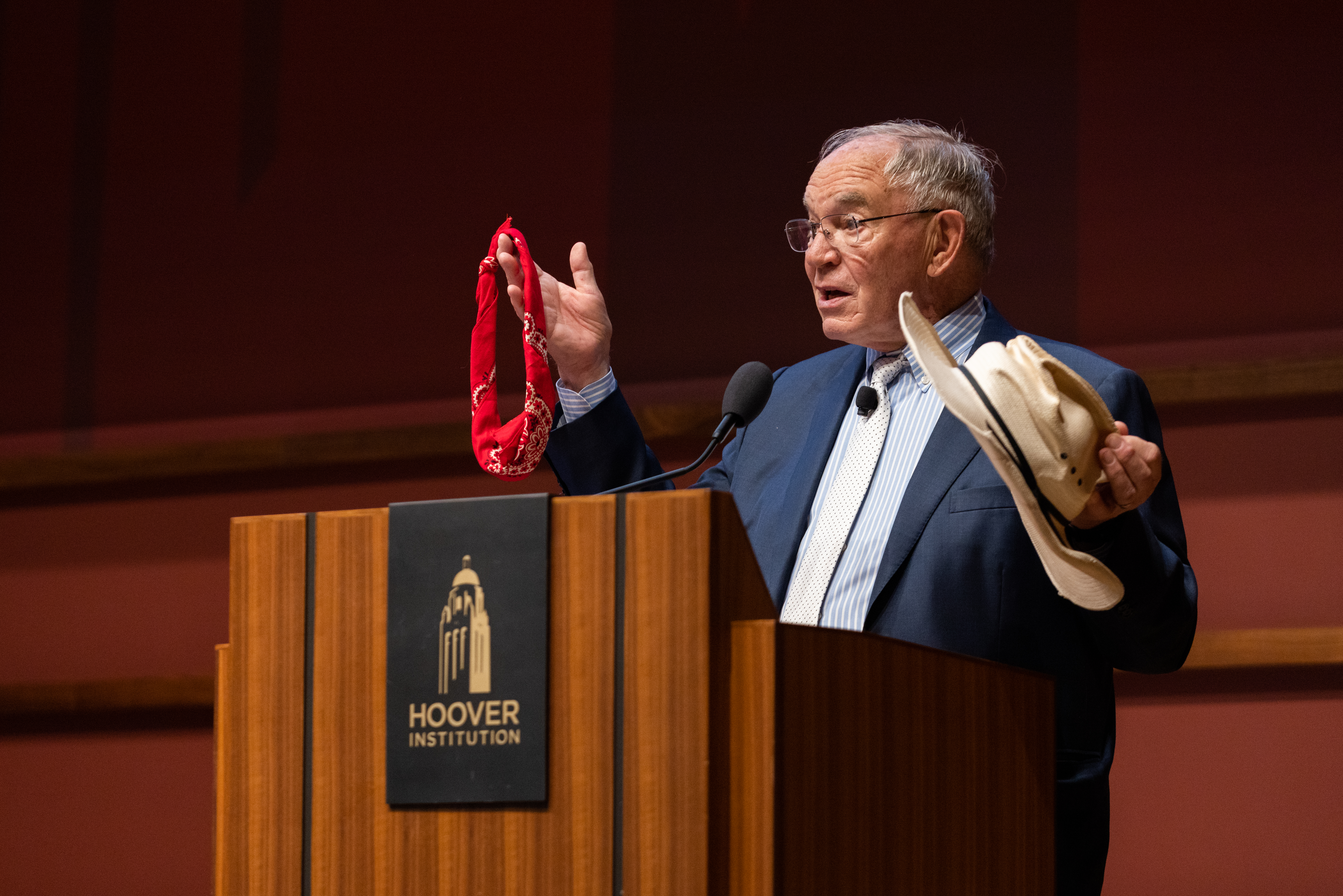 Terry Anderson introduces the Markets vs. Mandates Conference on April 8, 2024, using his rancher hat and a bandanna to describe differing views of ranchers versus environmentalists on reintroducing the wolf to pasturelands.