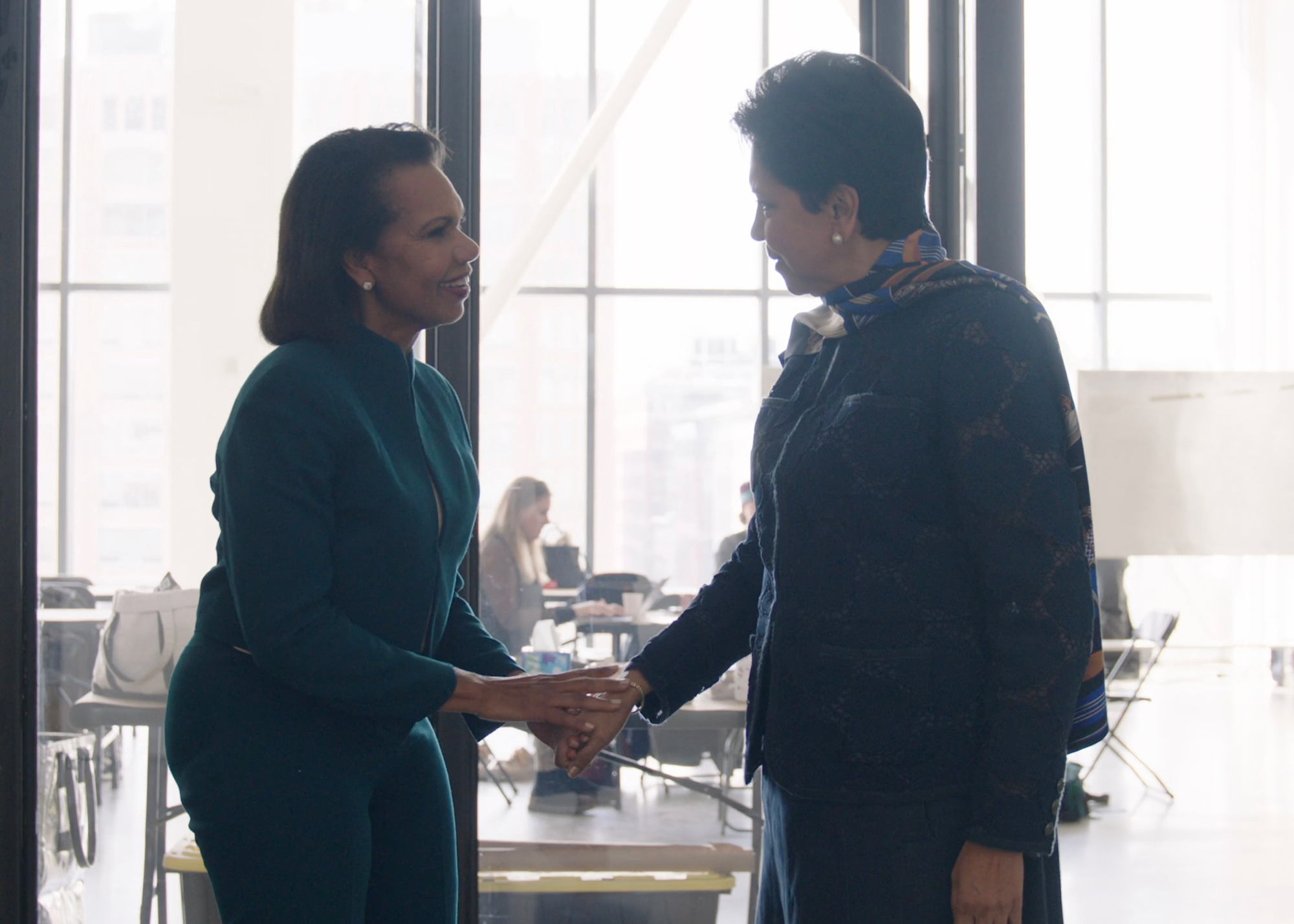 Condoleezza Rice and Indra Nooyi greeting one another on set.