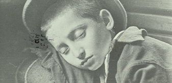 Detail of a black and white photograph of a young boy sleeping on a wooden bench, slight teal coloring.