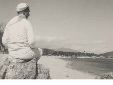 US Navy Seabee sits on a rock at a beach in the Pacific theater of World War II