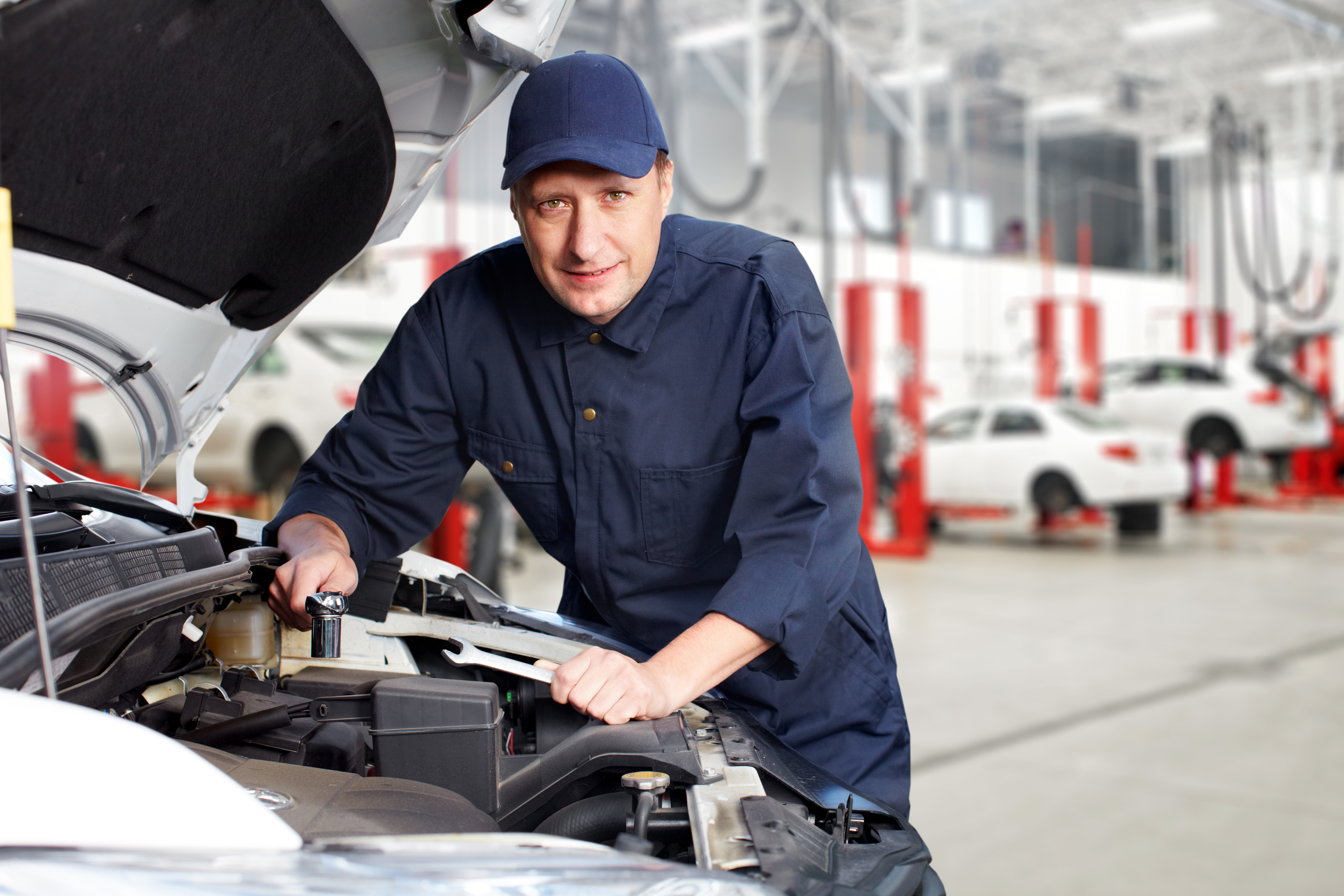 A white mechanic works on a car