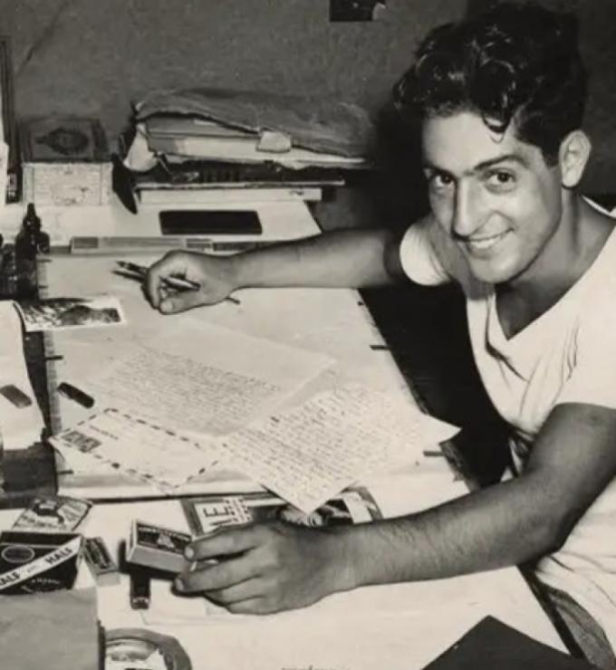 Nat Bellantoni writting a letter at his desk in a tent during World War II