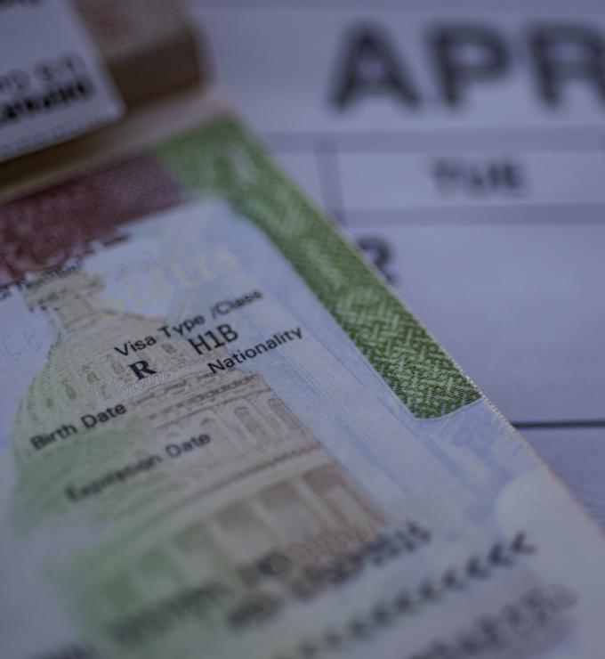 H1B visa (for specialty workers) stamp in passport, blurred april calendar on background. H1B visa program deadline concept. Close up view. stock photo