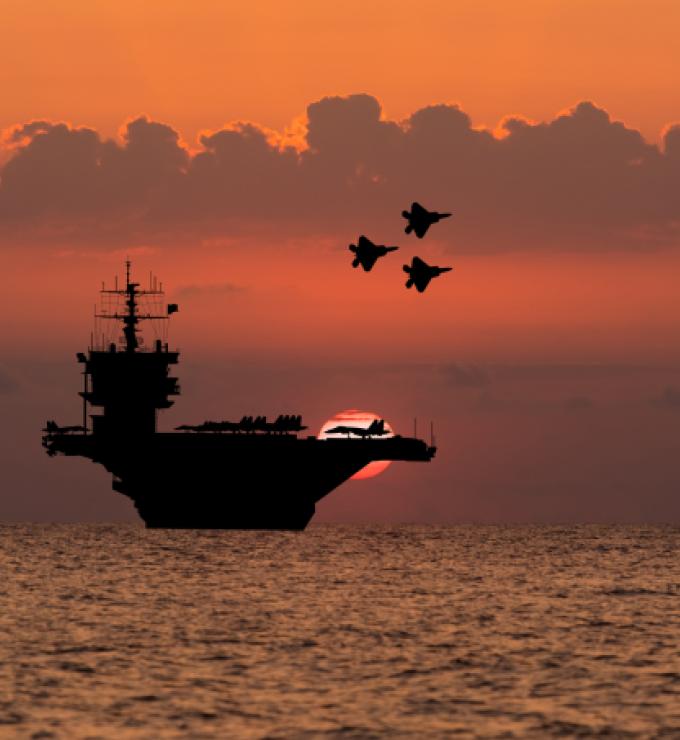 Aircraft carrier and fighters at sunset in the sea - stock photo