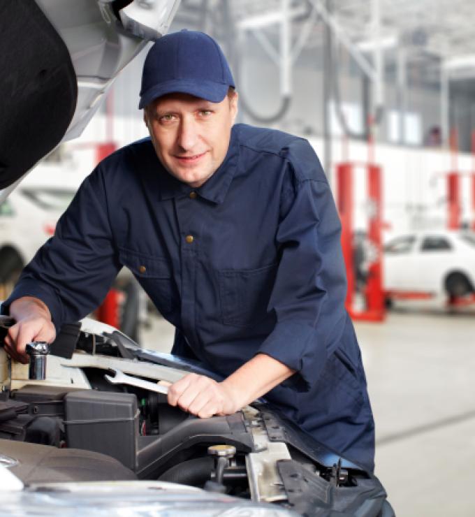 A white mechanic works on a car