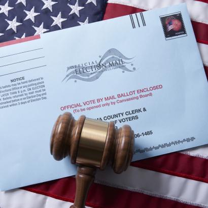 Voting ballot: Absentee voting by mail with ballot envelope on USA flag and gavel stock photo