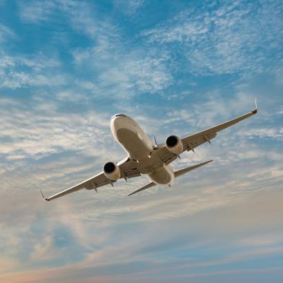 Airplane flying over tropical sea at sunset stock photo