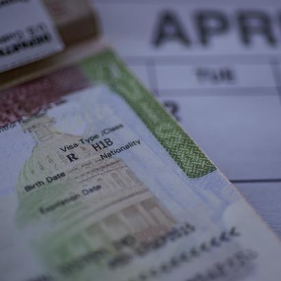 H1B visa (for specialty workers) stamp in passport, blurred april calendar on background. H1B visa program deadline concept. Close up view. stock photo