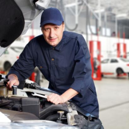 A white mechanic works on a car