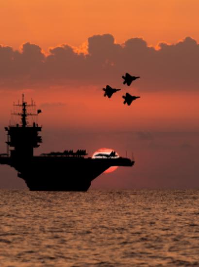 Aircraft carrier and fighters at sunset in the sea - stock photo