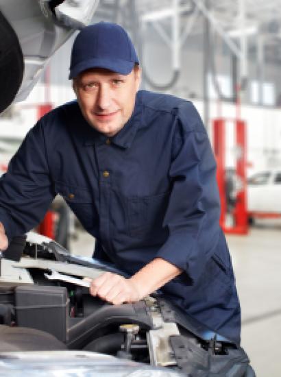 A white mechanic works on a car