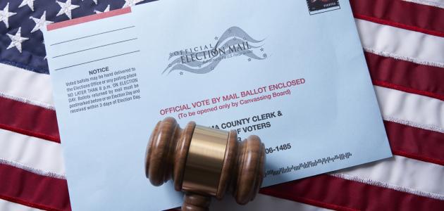 Voting ballot: Absentee voting by mail with ballot envelope on USA flag and gavel stock photo
