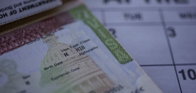 H1B visa (for specialty workers) stamp in passport, blurred april calendar on background. H1B visa program deadline concept. Close up view. stock photo