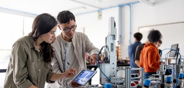 Team of students building a robotic arm in a STEM class stock photo
