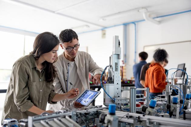 Team of students building a robotic arm in a STEM class stock photo