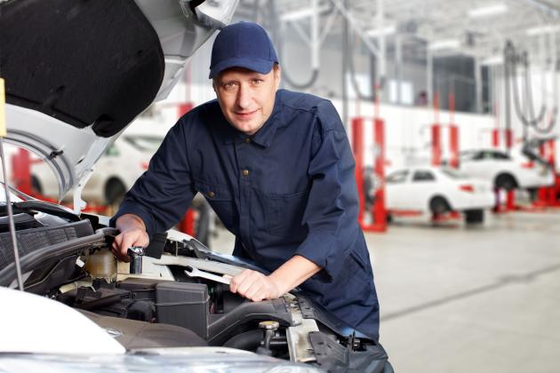 A white mechanic works on a car