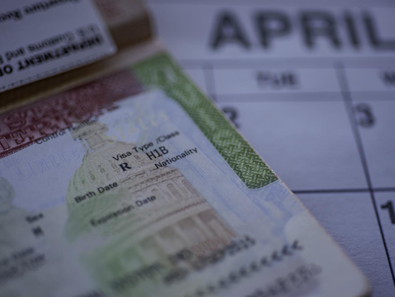 H1B visa (for specialty workers) stamp in passport, blurred april calendar on background. H1B visa program deadline concept. Close up view. stock photo