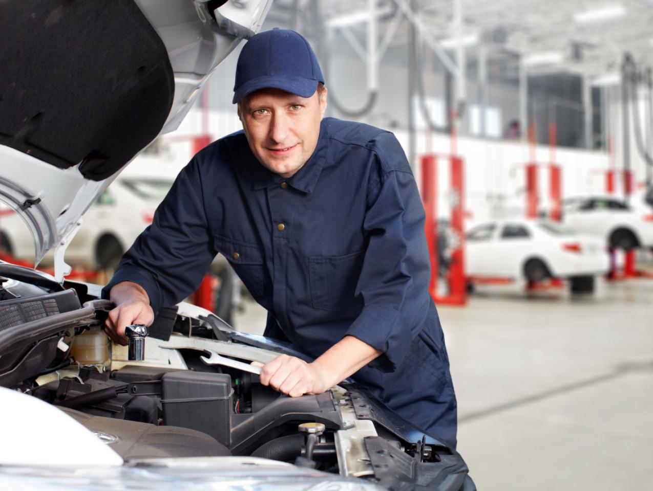 A white mechanic works on a car