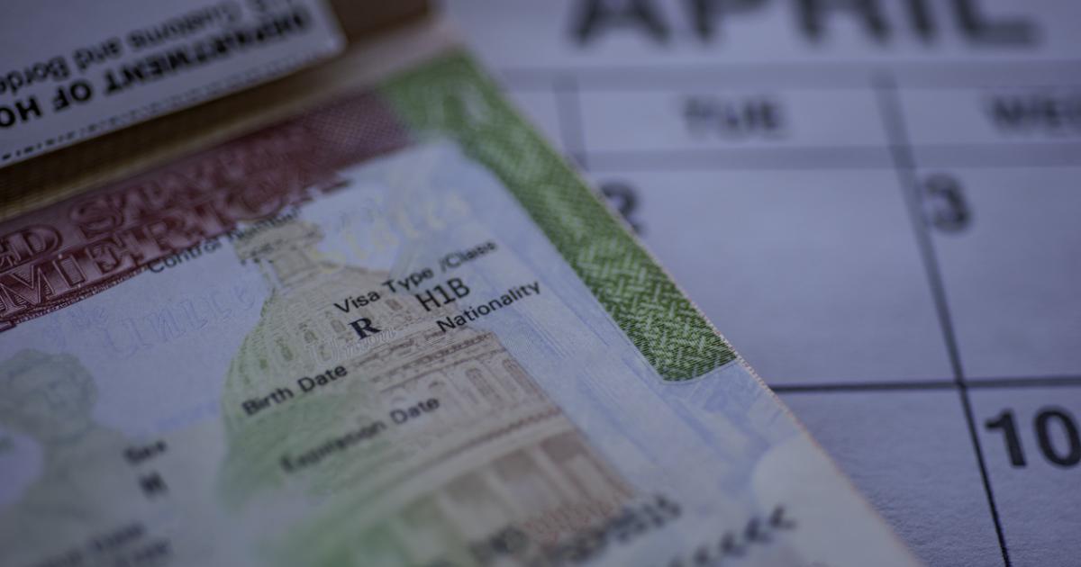 H1B visa (for specialty workers) stamp in passport, blurred april calendar on background. H1B visa program deadline concept. Close up view. stock photo