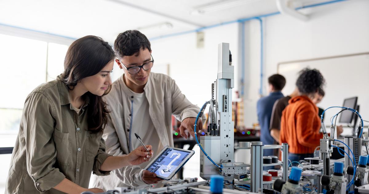 Team of students building a robotic arm in a STEM class stock photo