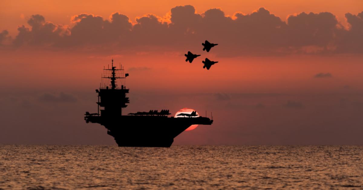 Aircraft carrier and fighters at sunset in the sea - stock photo