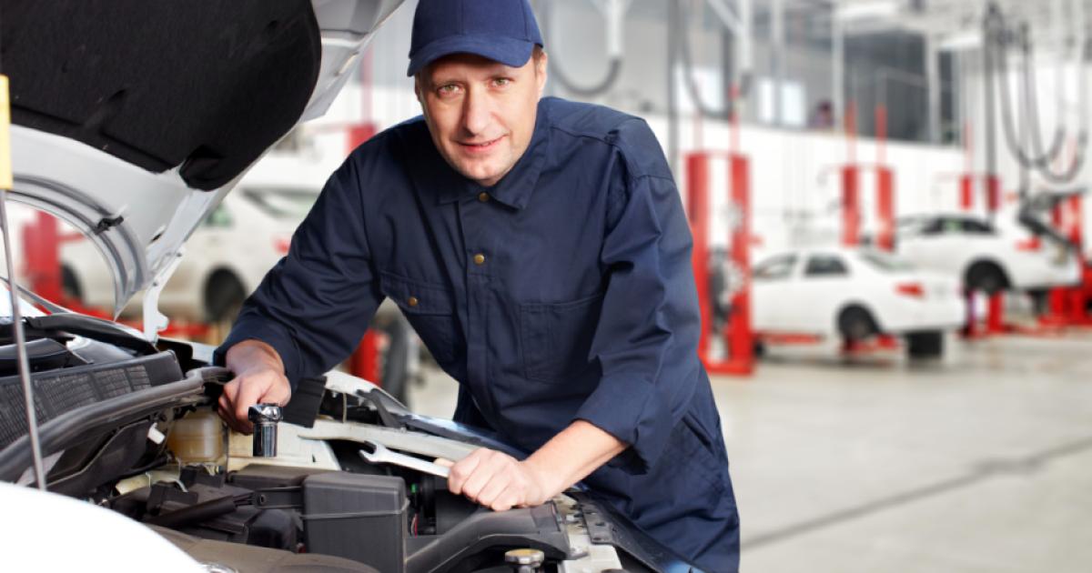 A white mechanic works on a car